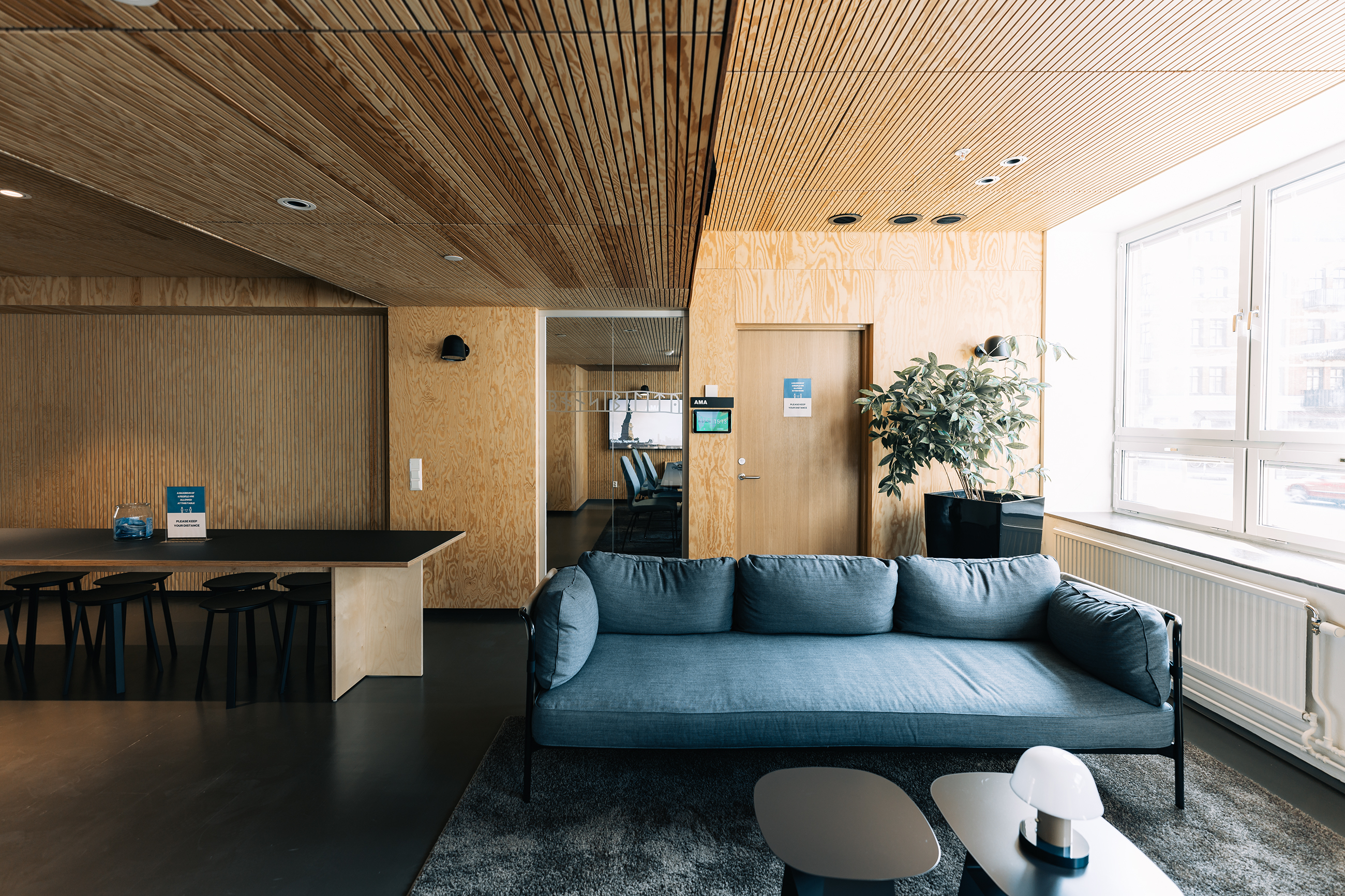 Sort sofa med blå puder i samlingsrum med træpanel på både væg og loft