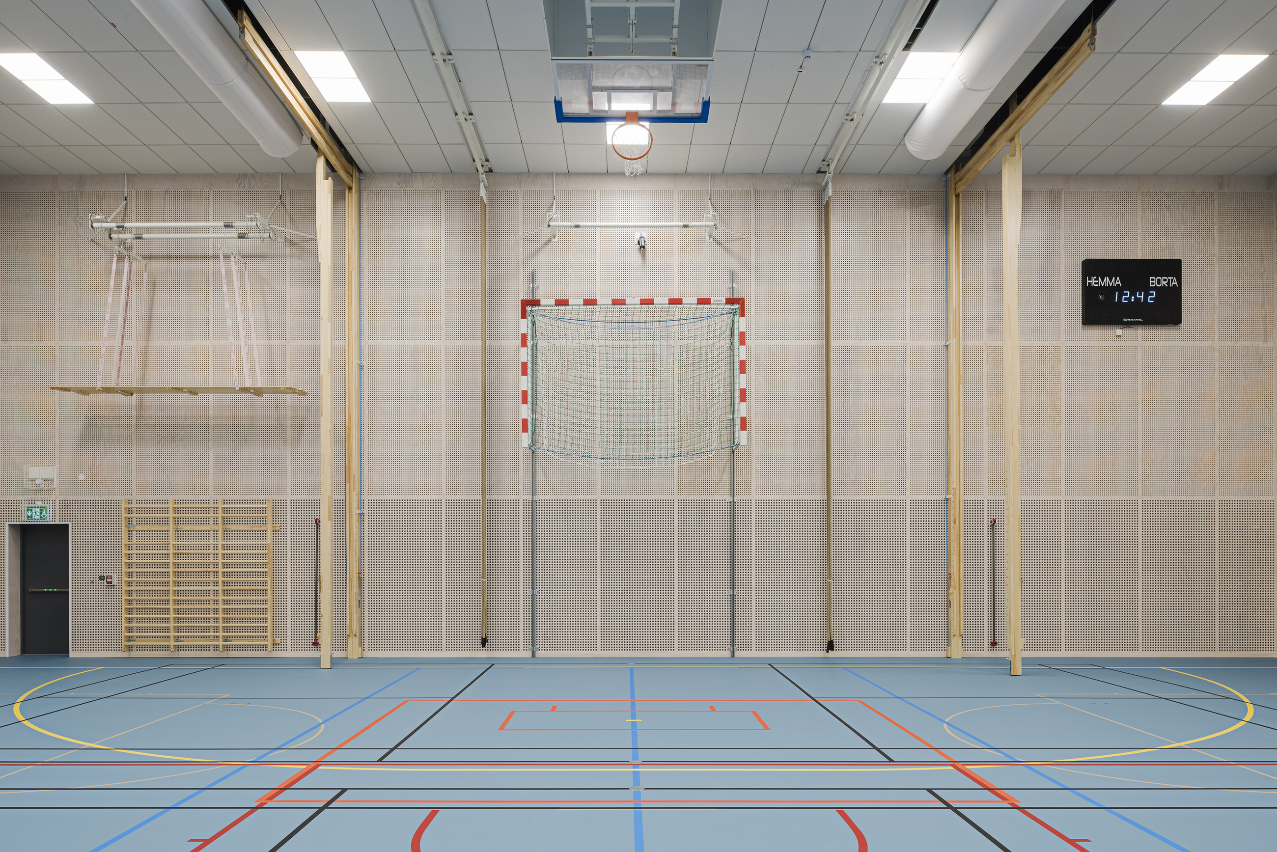 Gymnastiksal med perforerede paneler på væggene og ophøjet håndboldsmål